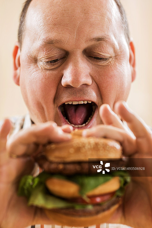 饥饿的胖男人准备吃一个巨大的汉堡图片素材