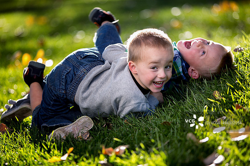 两个小男孩在公园草地上摔跤图片素材
