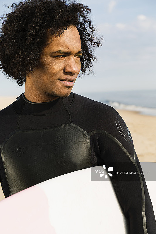 混血冲浪者在海滩上扛着冲浪板图片素材