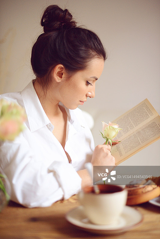 年轻女人一边吃早餐一边看书图片素材