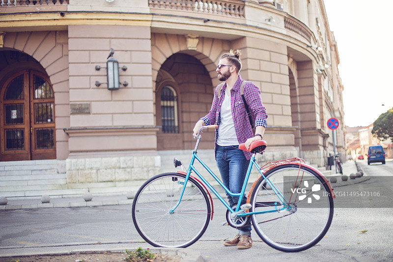 男人推着自行车穿过城市图片素材