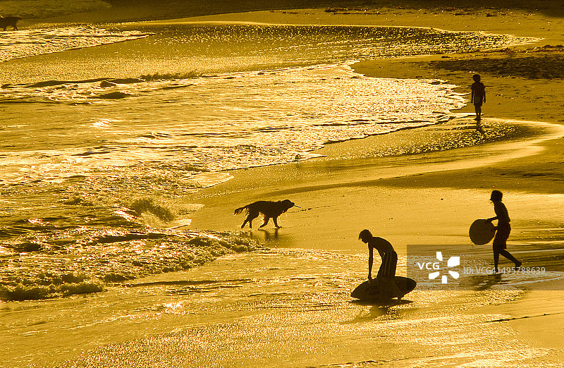 金色沙滩上的冲浪者剪影图片素材
