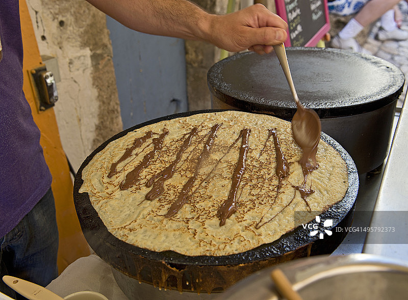 在法国韦尔东峡谷拉帕吕，男子准备淋上巧克力酱的法式可丽饼图片素材