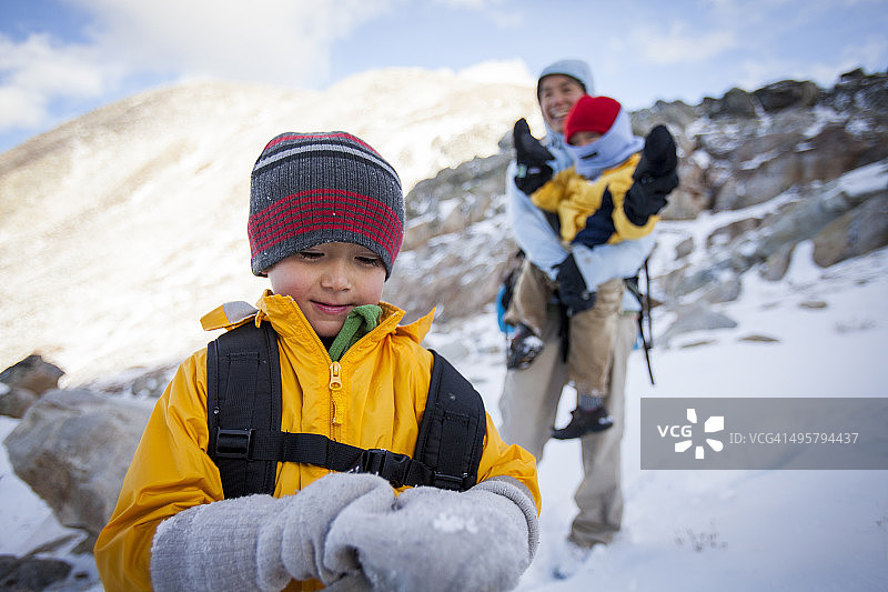 母子在白雪皑皑的山间小路上徒步旅行图片素材
