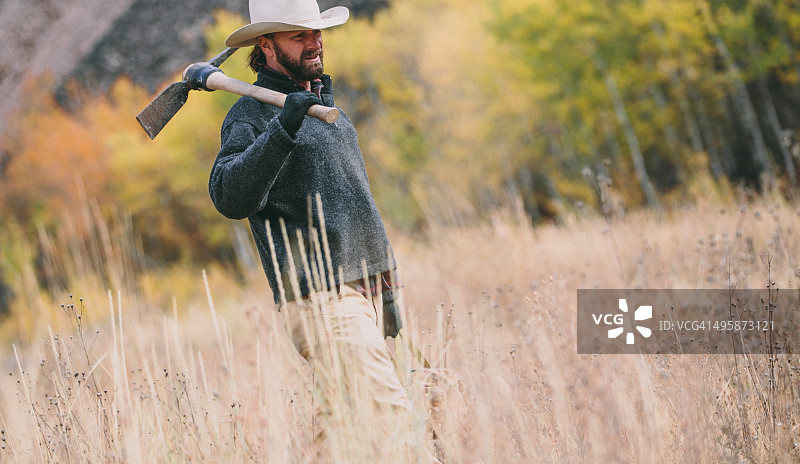 携带工具走在田野中的健壮男人图片素材