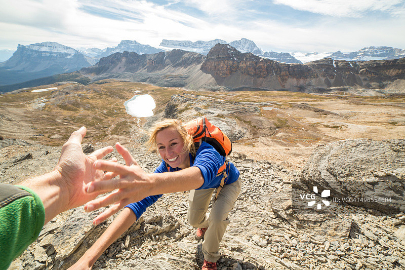 年轻女子攀岩，伙伴伸出援手图片素材
