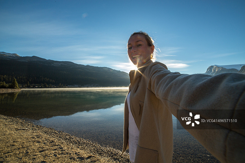 年轻女子以壮丽的山湖景色自拍图片素材