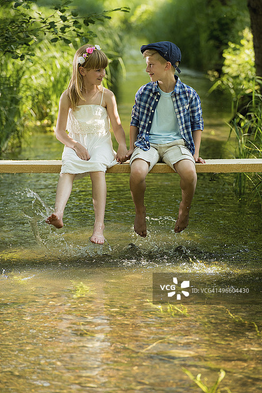 孩子们坐在小溪上的木头上图片素材