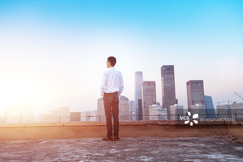 商人看着阳光下的城市景观图片素材