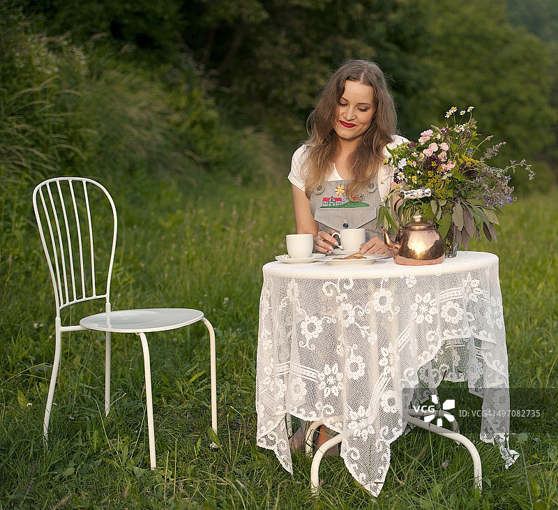 年轻女子在草地上享用下午茶图片素材
