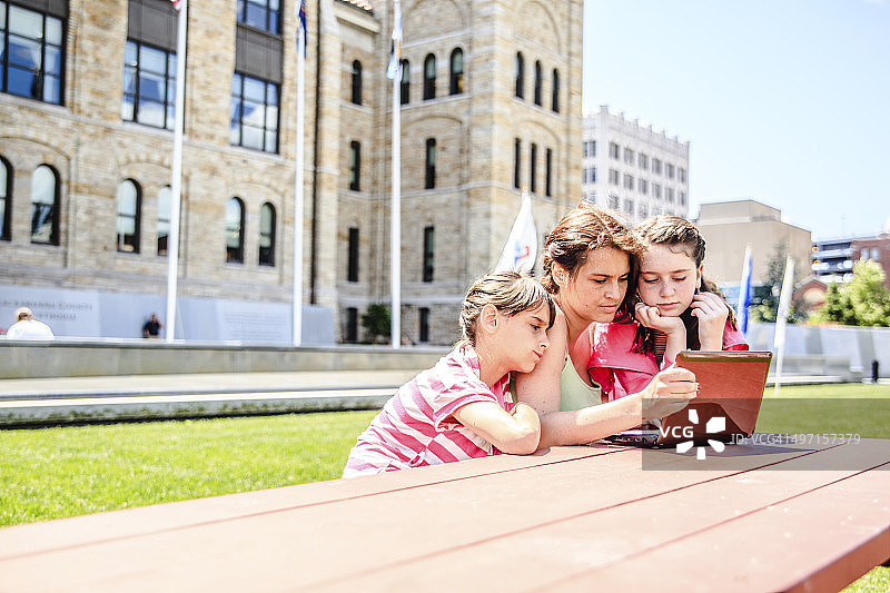 家庭，母亲和两个女儿在笔记本电脑上看资料图片素材