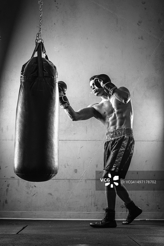 黑白照片中击打拳击沙袋的西班牙裔男子图片素材