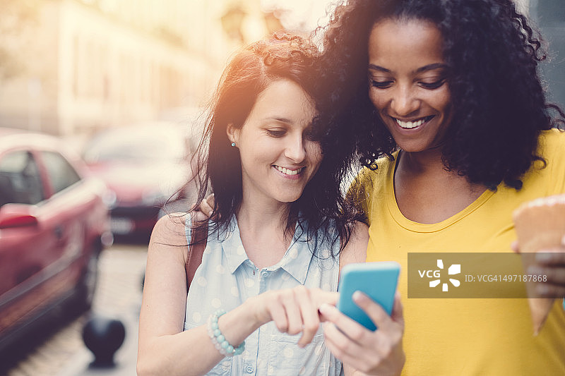 在城市里用智能手机发短信的女孩们图片素材