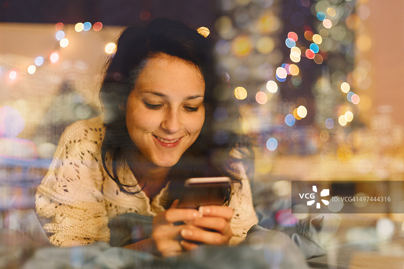 在床上发短信庆祝圣诞节的女孩图片素材