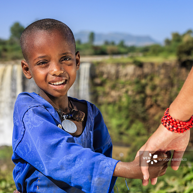 白人女性牵着非洲儿童的手图片素材