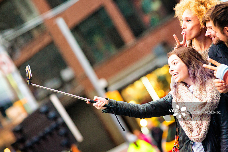 一群年轻人用自拍杆拍摄搞怪自拍照图片素材