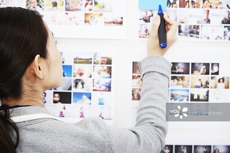 年轻女人看着照片，手持笔图片素材