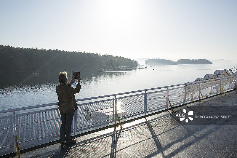男子在渡轮上用平板电脑拍照图片素材