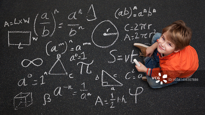 在街上用粉笔画科学图画的可爱男孩图片素材