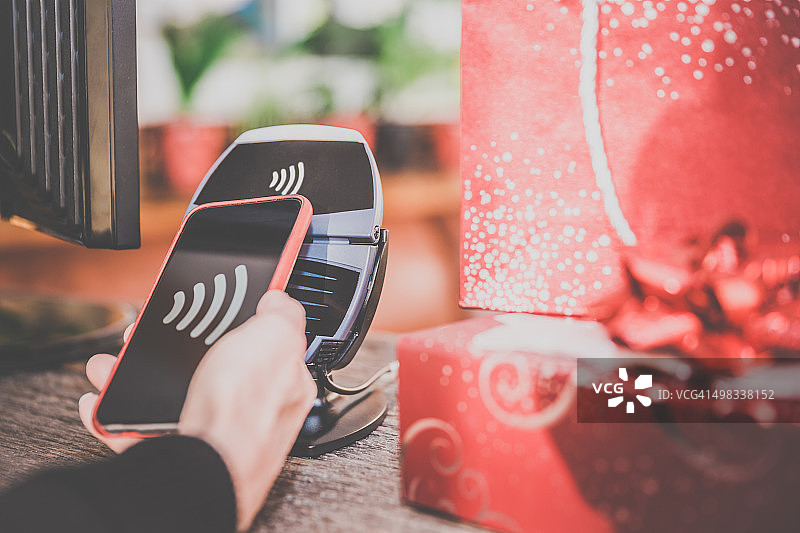 在商店用智能手机上的NFC技术支付的女人图片素材