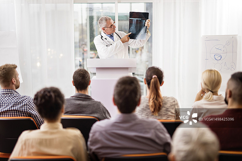 在教育活动中分析X光片的年长医生图片素材