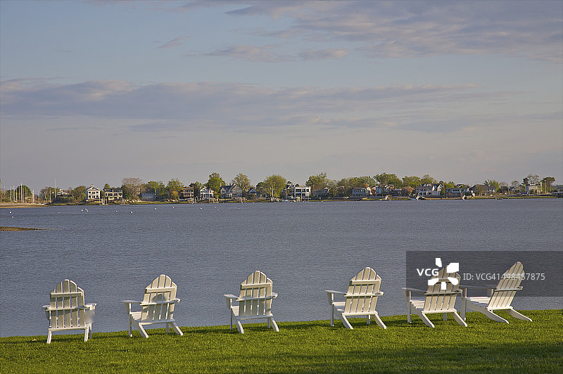 六把白色椅子面向水面和岸边房屋图片素材