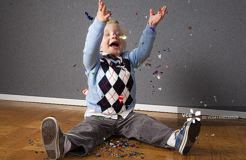 微笑的幼儿男孩抛洒五彩纸屑图片素材