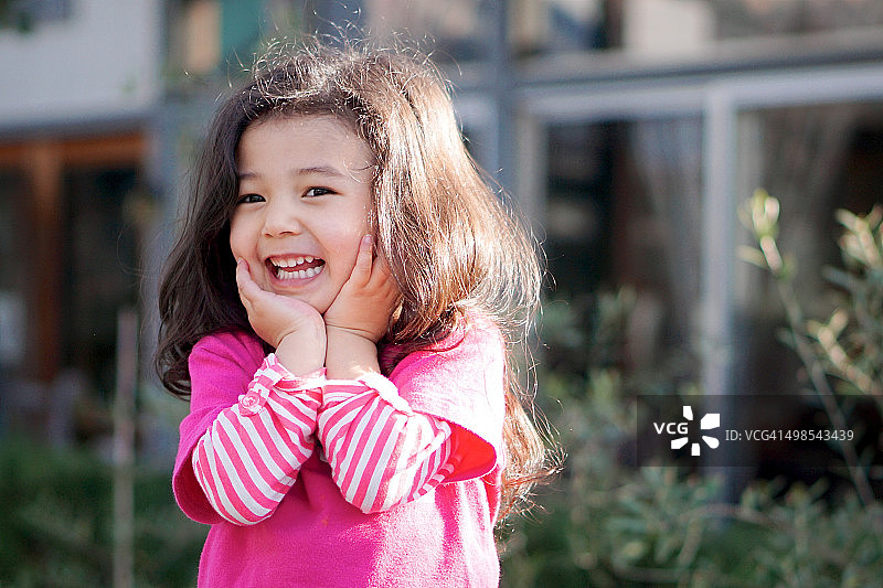 双手托着下巴，穿着粉色衬衫的微笑女孩图片素材