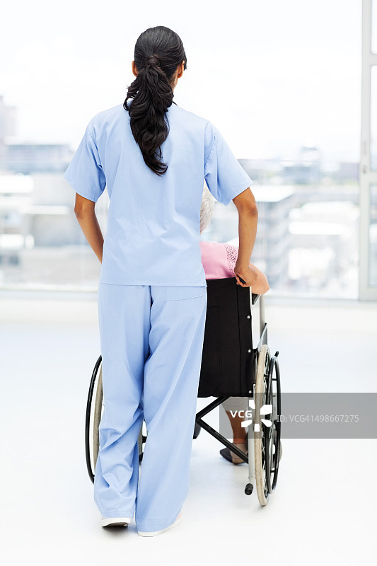 在疗养院，护士用轮椅推着老年妇女图片素材