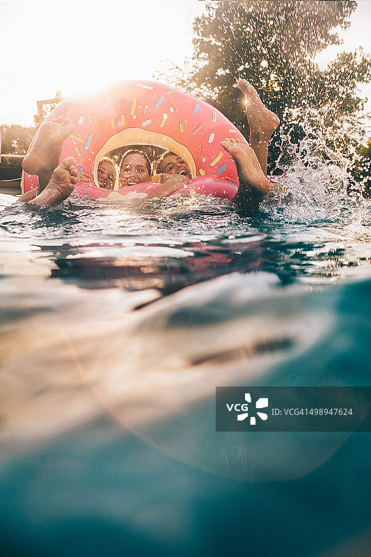 女孩们在游泳池里用粉色充气玩具嬉戏和大笑图片素材