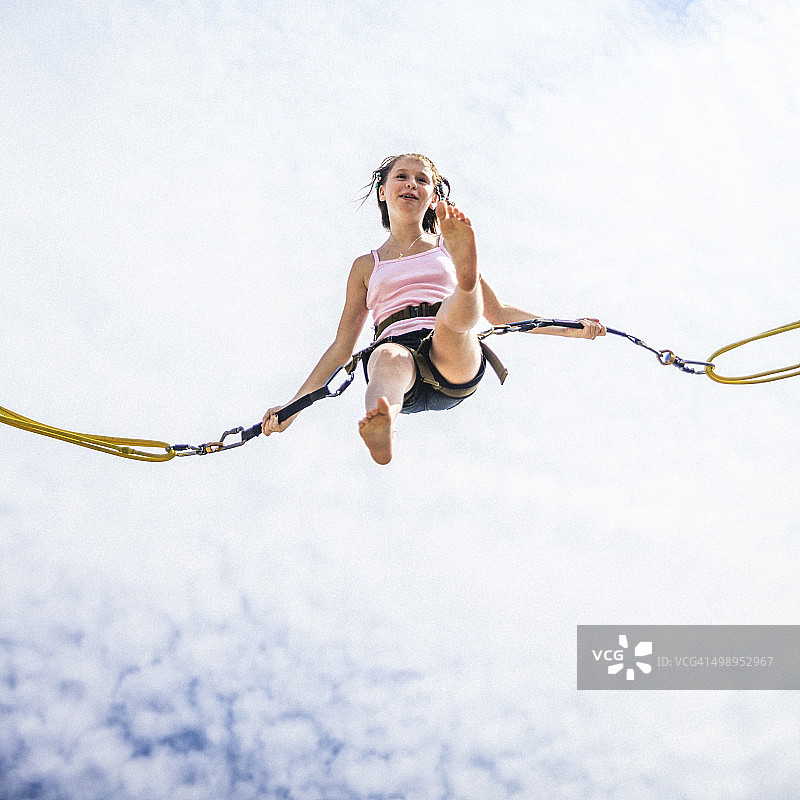 在蹦床上玩蹦极的少女图片素材