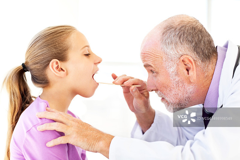 资深医生用压舌板检查女孩的口腔图片素材