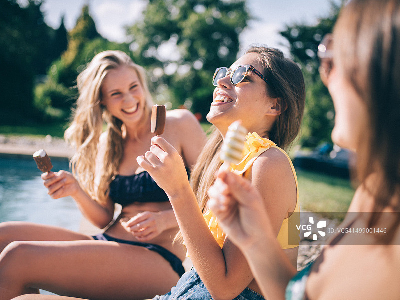 少女朋友们在泳池边吃冰淇淋，开怀大笑图片素材