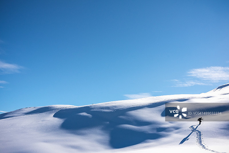 徒步者在雪山坡上行走图片素材