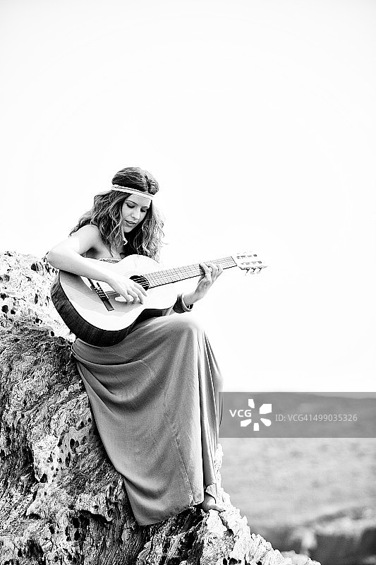 在悬崖上弹吉他的年轻嬉皮士女子，拉科鲁尼亚图片素材