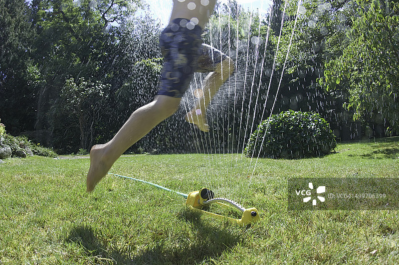 男孩在洒水器中的脚图片素材
