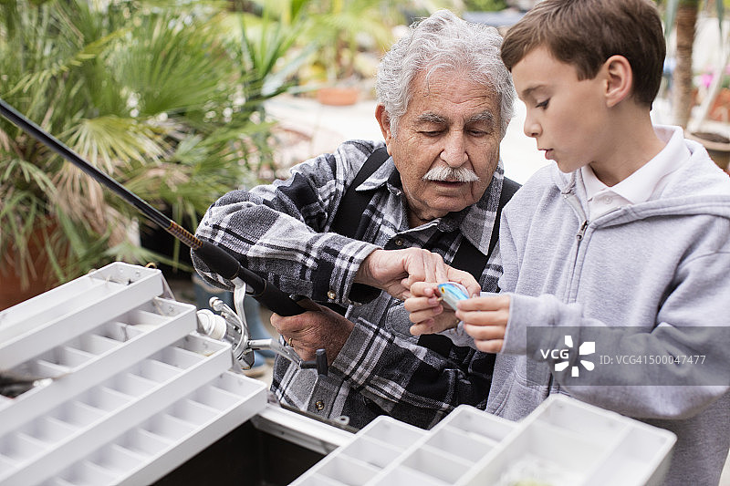 年长的白人男子和孙子检查钓鱼竿图片素材