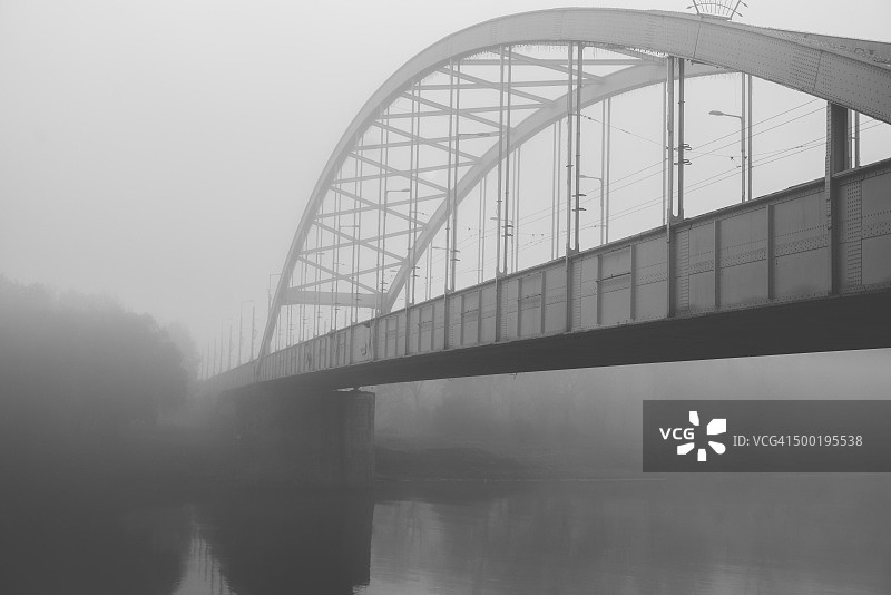 秋季清晨薄雾中蒂萨河上的钢桥，河对岸可见森林图片素材