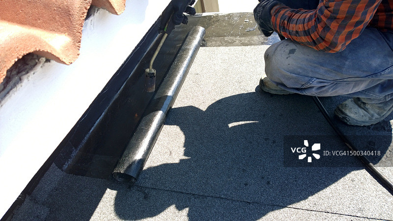 屋顶工准备用燃气加热器喷枪融化沥青屋顶毡卷图片素材