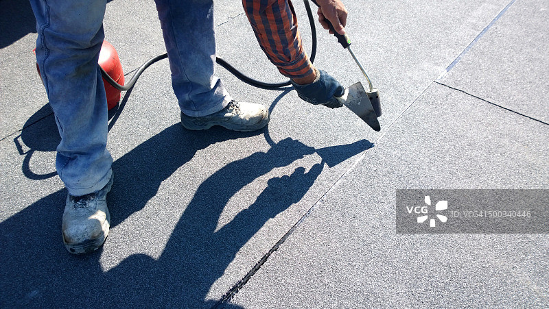 屋顶工准备用燃气加热器喷枪融化沥青屋顶毡卷图片素材