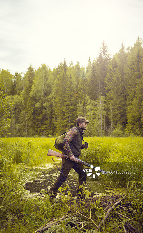 猎人在森林附近的沼泽地中跋涉图片素材