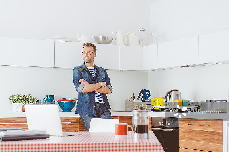 高兴的男人站在家里的厨房里图片素材