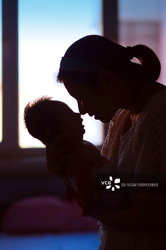 年轻母亲抱着满月的宝宝，想要亲吻图片素材