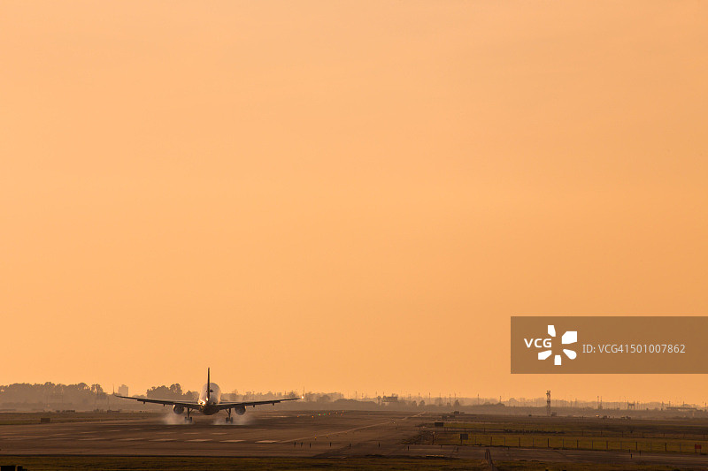 飞机在巴塞罗那埃尔普拉特机场的日落光线下着陆，轮子冒烟图片素材