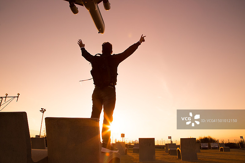 在机场观景点举起手臂，思考飞机着陆的兴奋男人图片素材