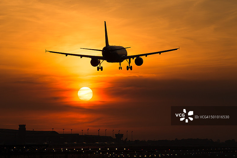 飞机在巴塞罗那埃尔普拉特机场降落，地平线上的魔幻日落图片素材