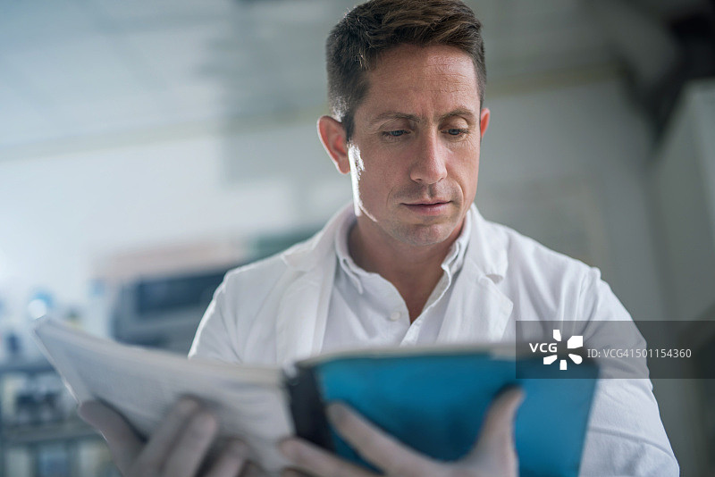 中年医生从书中阅读医疗数据图片素材