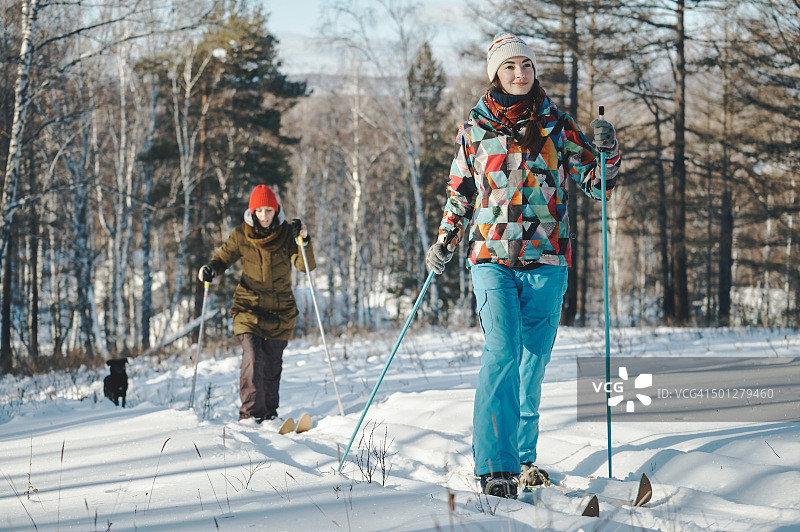 女孩们在冬季森林里滑雪图片素材