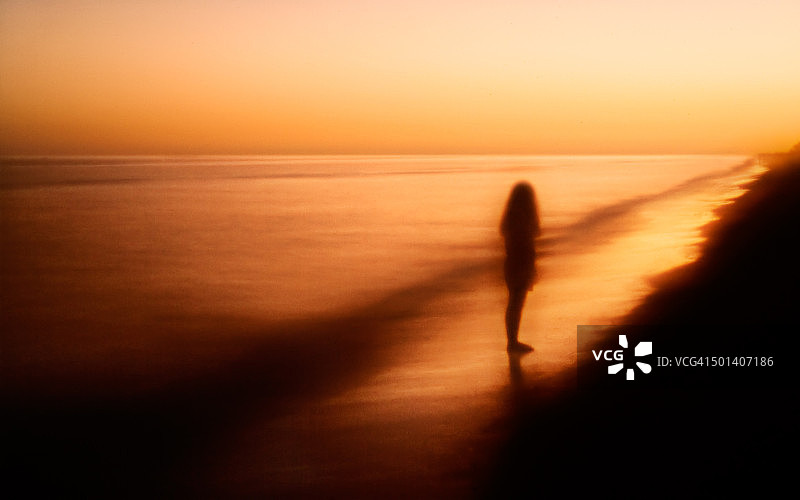 日落时分，海滩上女孩的剪影，柔焦和梦幻般的感觉图片素材