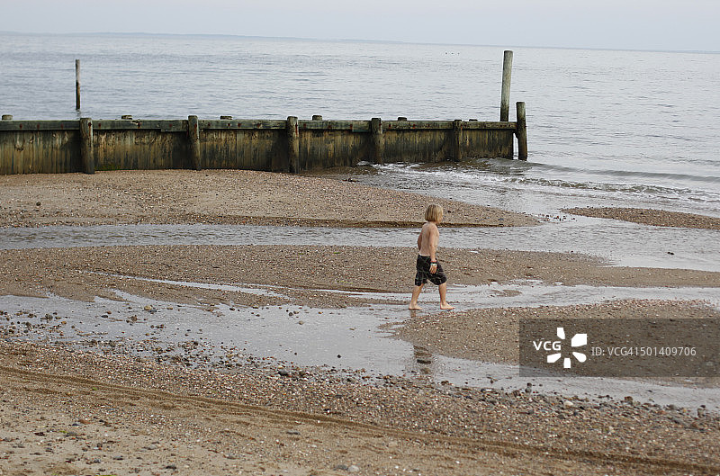 男孩在沙滩上走向水边图片素材